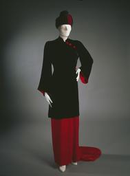 Vorschaubild zu  'Hauskleid aus schwarzem und rotem Seidensamt mit asymmetrischem Knopfverschluss auf der linken Schulter und Turban aus rotem und schwarzem Stoff mit abgesteppten Formen'