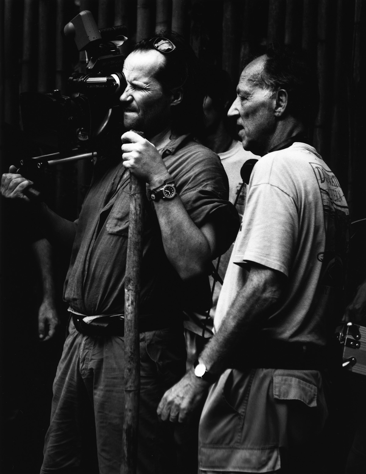 Schwarz-weiß-Foto: Der Regisseur steht neben seinem Kameramann, der durch den Sucher blickt.