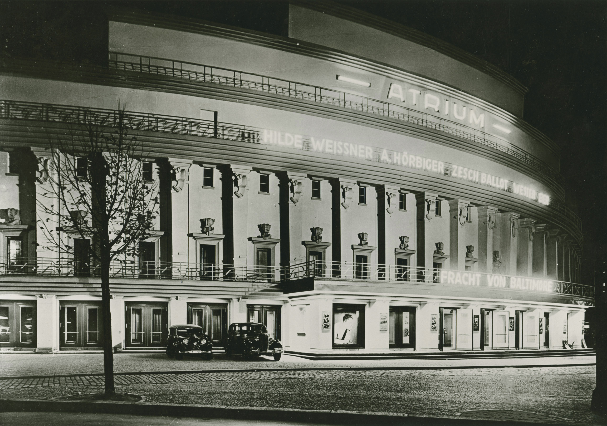 Schwarz-Weiß-Foto: nächtliches Kinogebäude mit Leuchtreklame
