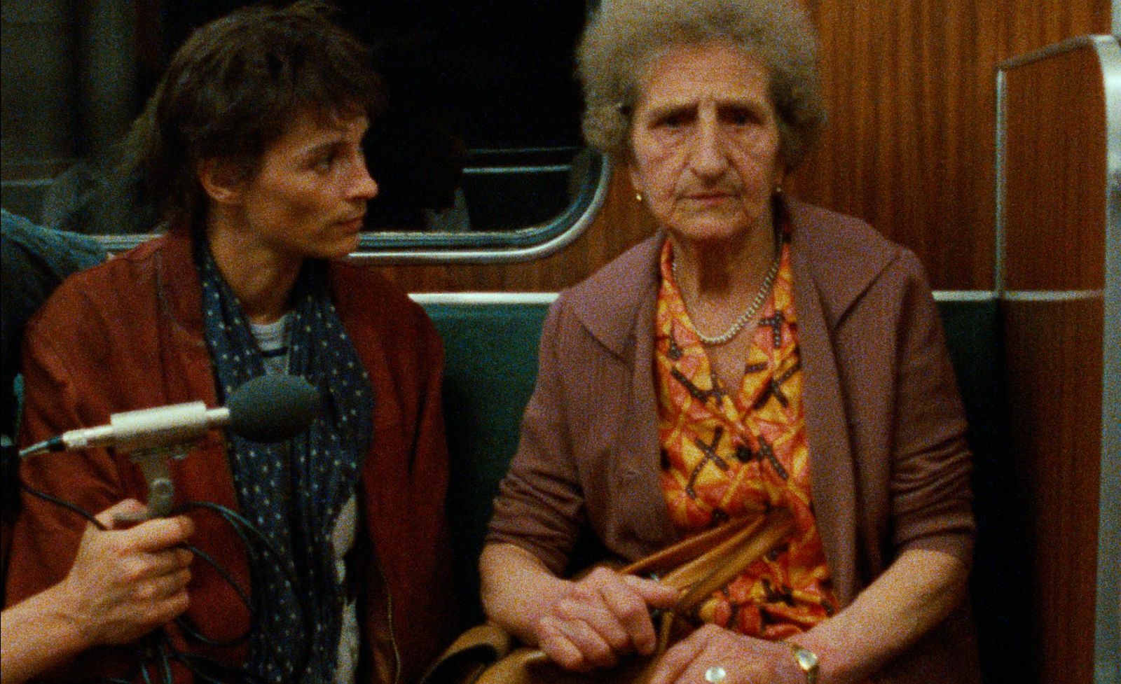 Die Regisseruin sitzt mit einer älteren Frau in der U-Bahn-Linie 8