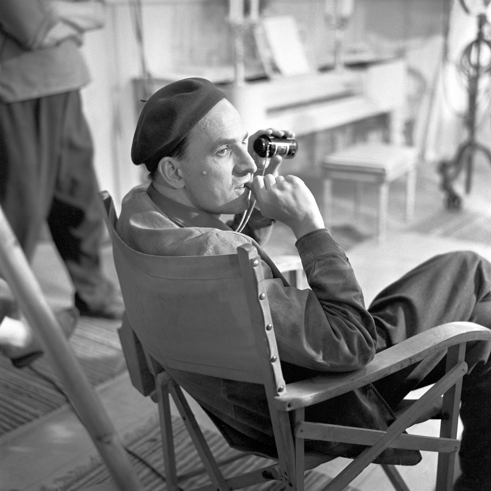 Black and white portrait of Ingmar Bergman sitting in a chair on set