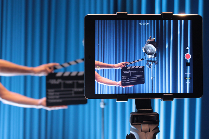 Camera and clapperboard in front of a blue curtain