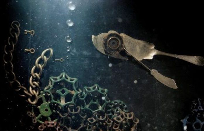 Dunkles Foto von einem Fisch im Wasser, gelegt aus mechanischen Metallteilchen
