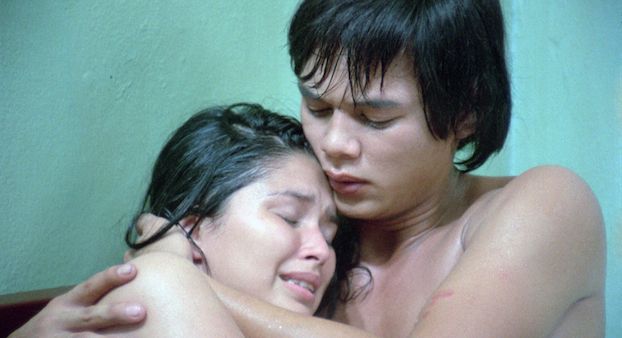 Eine junge Frau liegt mit verzerrtem Gesicht im Arm eines jungen Mannes, beide sind nackt.