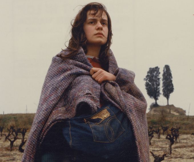 Eine junge Frau steht in eine dicke Decke gehüllt auf einem Feld.
