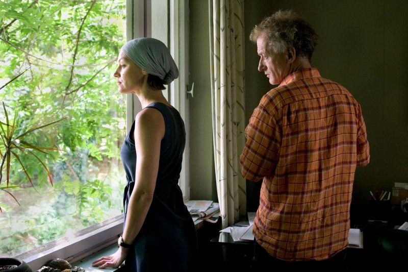 Eine Frau und ein Mann sehen aus einem Fenster im ersten Stock in den Garten.