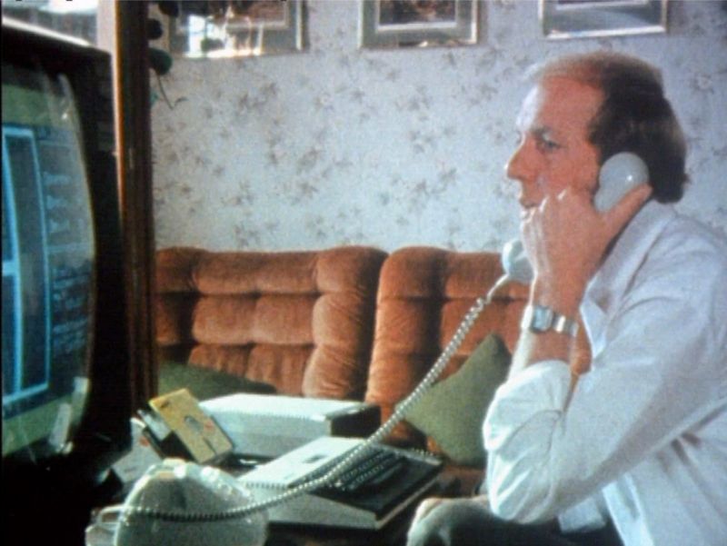 Ein Mann mit Telefonhörer vor einem Computer