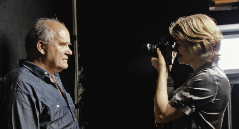 Film still of a woman filming a man, in color.