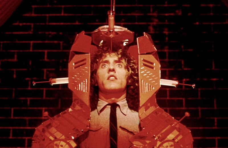 Szenenfoto: Der Kopf eines Mannes, eingespannt in einer Maschine