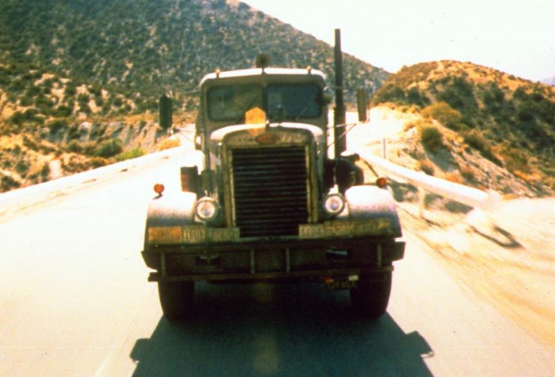 Still in color: A truck driving down a desert road.