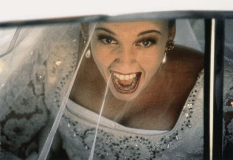 Still in color: Close-up of a screaming bride through a car window.
