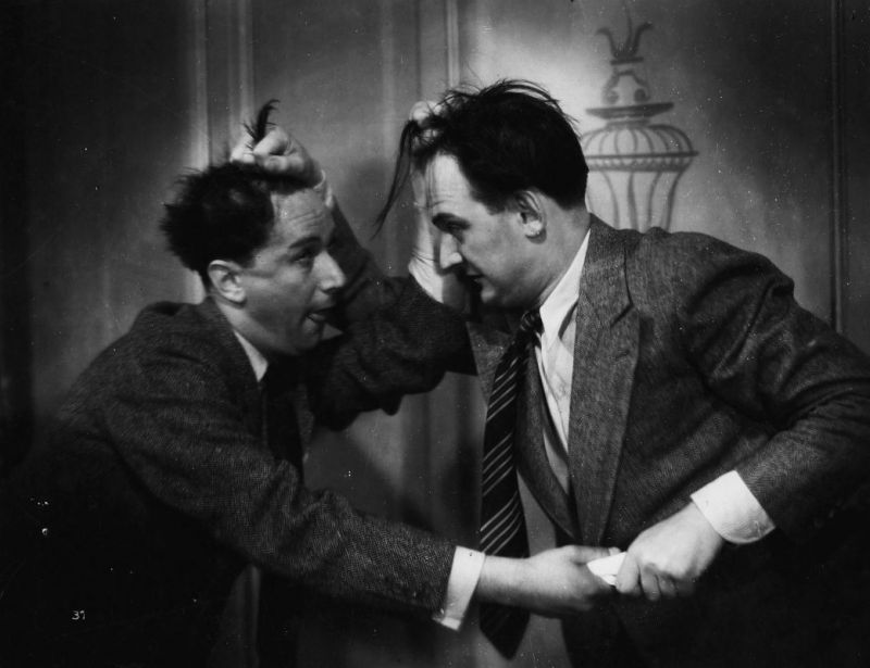 Two men are fighting, grabbing each other by the hair and pulling something with the other hand. 
