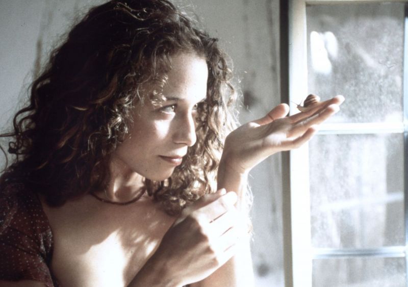 Szenenfoto: Eine Frau hält eine Schnecke auf der Hand und hält sie vor ihr Gesicht.