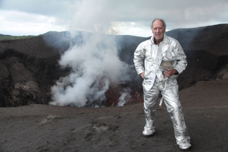 Der Regisseur steht in Schutzkleidung am Krater eines Vulkans