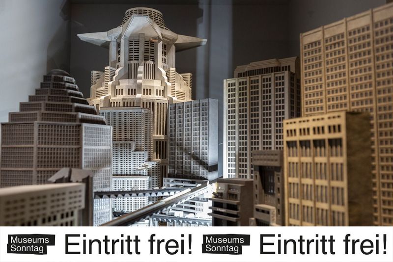 Foto des Modells der Stadt aus dem Film ›Metropolis‹ mit dem Banner »Museumssonntag – Eintritt frei!«