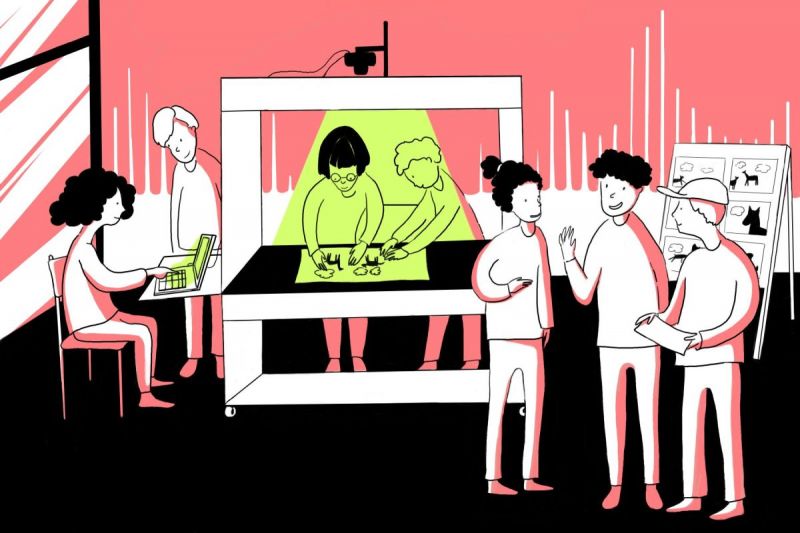 Eine Gruppe Kinder steht um eine Trickbox, zwei basteln, zwei sitzen an einem Computer neben der Box und drei stehen davor.