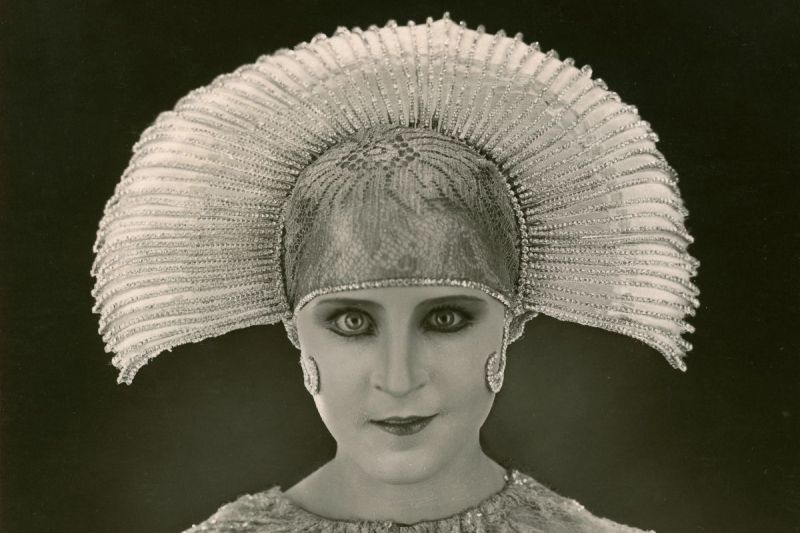 Kostüm der »Maschinen-Maria«: Ein Porträt einer Frau vor dunklem Hintergrund mit einem glitzernden Kopfschmuck und Oberteil