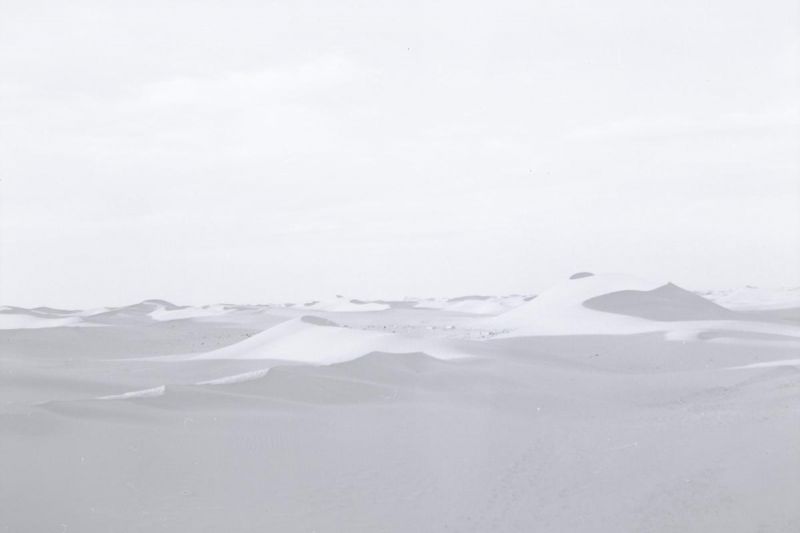 Szenenfoto in Farbe: Ein Foto von der Wüste, in dem der Sand und der Himmel so hell sind, dass sie kaum voneinander zu unterscheiden sind.