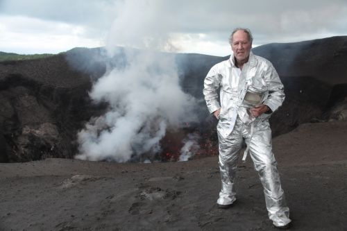 Der Regisseur steht in Schutzkleidung am Krater eines Vulkans.
