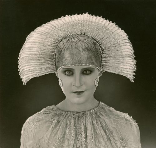 Black and white portrait of a woman with a sparkling head piece and shirt.