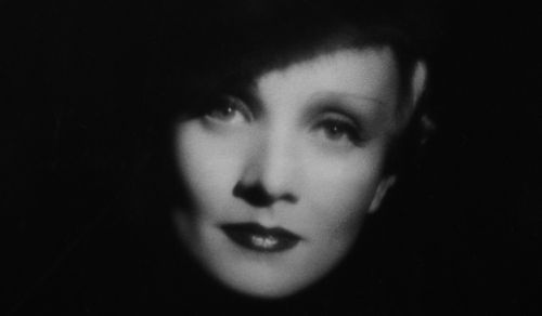 Das Gesicht der Schauspielerin Marlene Dietrich wird umrahmt von einem dunklen Hintergrund.