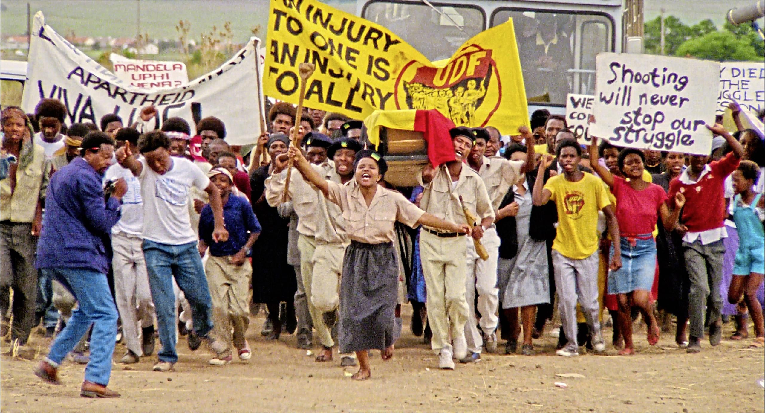 Szenenfoto in Farbe: Ein Protest von Schwarzen Menschen gegen die Apartheid in Süd-Afrika.