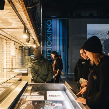 Menschen in einer Ausstellung betrachten ausgezogene Vitrinen-Schubladen.