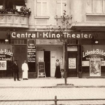 Drei Personen und ein Hund vor einer Kinofassade in Berlin, Schwarzwei&szlig;aufnahme aus dem Jahr 1910.