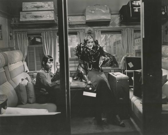 Schwarzes und wei&szlig;es Foto von zwei Frauen in einem Zugabteil. Sie sind altmodisch gekleidet und gucken streng. 
