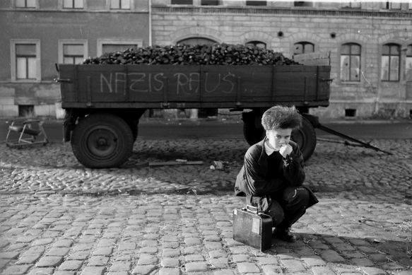 Ein kleiner Junge kniet vor einem Wagen, auf den die Worte Nazis raus gemalt sind.