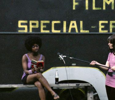 Two women at a film production, one reading on a bench, the other holding a boom mic. In the background: FILM SPECIAL-EFFECTS in yellow letters.