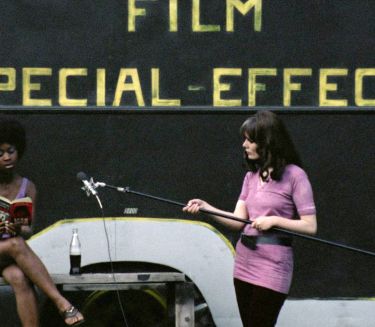 Two women at a film production, one reading on a bench, the other holding a boom mic. In the background: FILM SPECIAL-EFFECTS in yellow letters.