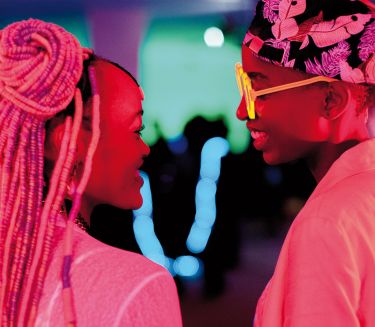 Zwei Personen, die sich ansehen, in pinkem Licht.