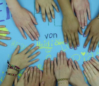 Screenshot aus einem Trickfilm, der in einem Workshop entstanden ist: Kinderh&auml;nde liegen auf einem hellblauen Papier, auf dem die Namen derer, die den Film gemacht haben, stehen.