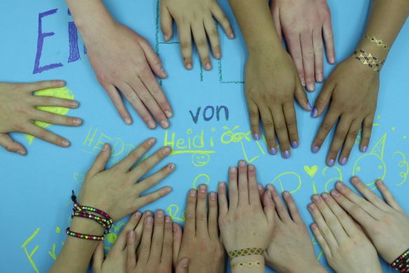 Screenshot aus einem Trickfilm, der in einem Workshop entstanden ist: Kinderhände liegen auf einem hellblauen Papier, auf dem die Namen derer, die den Film gemacht haben, stehen.