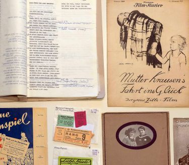 Various written copies are spread out on the table.