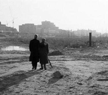 Zwei Personen stehen mit dem R&uuml;cken zur Kamera auf einem verlassenen Gel&auml;nde und gucken in die Ferne. Es ist eine schwarz-wei&szlig;e Fotografie.