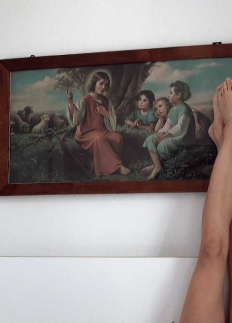 Ausgestreckte nackte Beine vor einem Gemälde an der Wand.