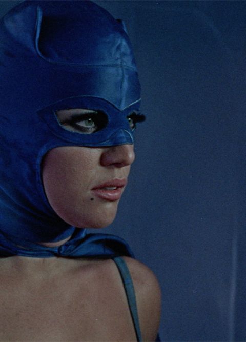 Eine Frau mit langen Wimpern in einer blauen Kostümmaske blickt zur Seite.