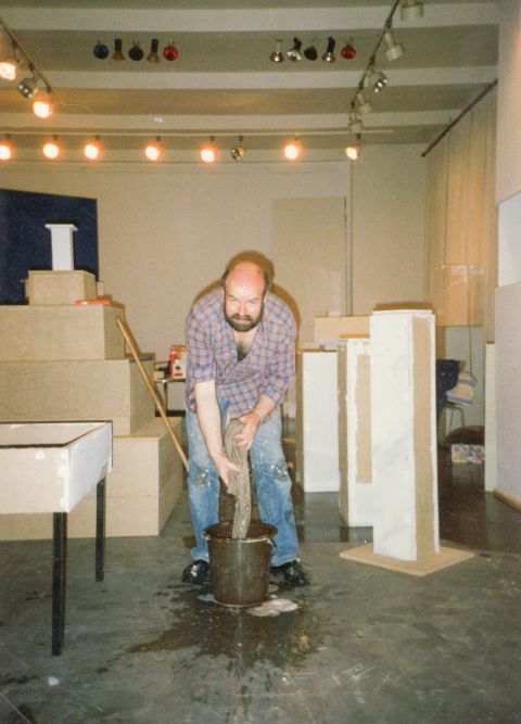 Ein Mann, Wolfgang Theis, steht in einem Museumsraum und wringt einen Mob aus.