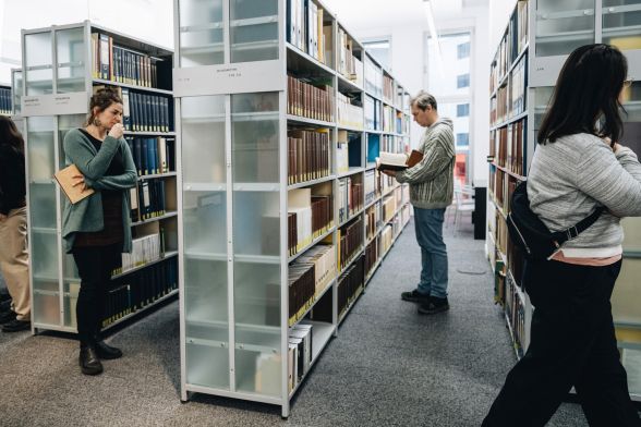 Personen in einer Bibliothek, die B&uuml;cherregale betrachten
