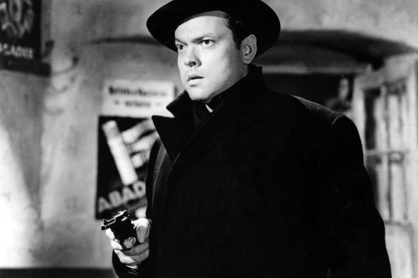 A man is aiming a pistol at something or someone with a determined expression on his face.