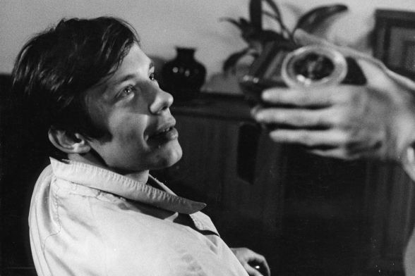 A man is smiling as he looks up at someone whose hands are holding a camera.
