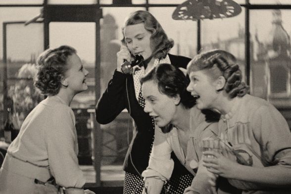 Four women, including Ingrid Bergman on the phone, with blonde and brunette hair, are amused by something.