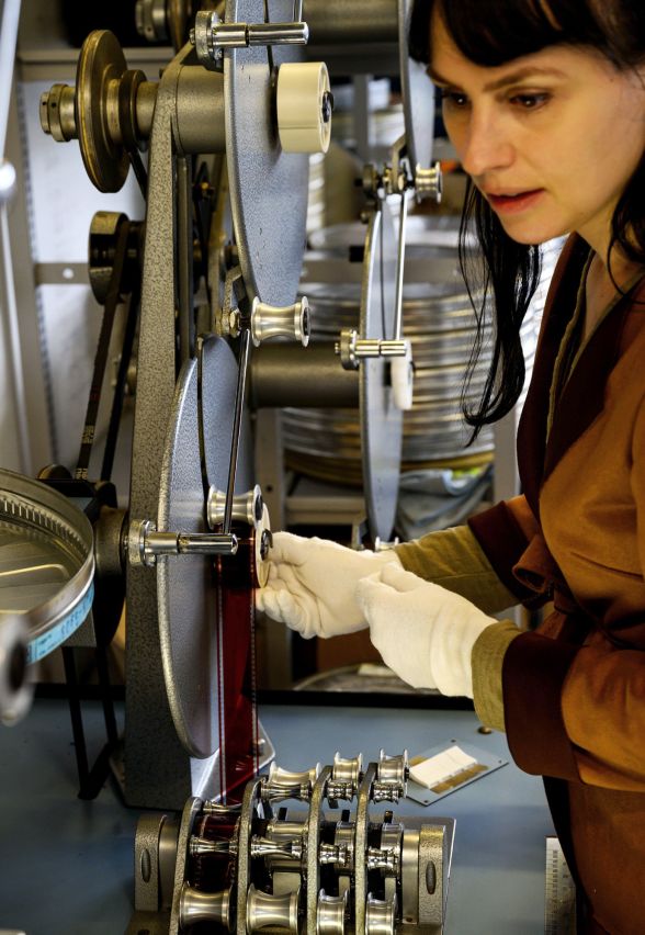 Eine junge Filmrestauratorin bereitet analoge Filmmaterialien am Abziehtisch zum Abgleich vor.