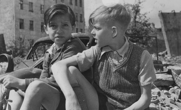 Zwei Jungen sitzen im vom Krieg zerstörten Berlin