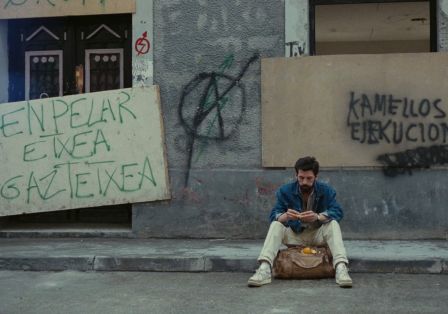 Ein Mann sitzt auf der Bordsteinkante einer Stra&szlig;e. Im Hintergrund sieht man Graffiti und versperrte T&uuml;ren sowie Fenster. 