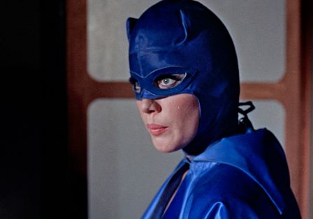 Eine Frau mit langen Wimpern in einer blauen Kost&uuml;mmaske blickt zur Seite.