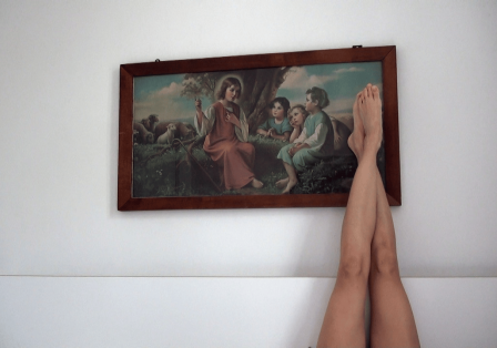 Ausgestreckte nackte Beine vor einem Gem&auml;lde an der Wand.