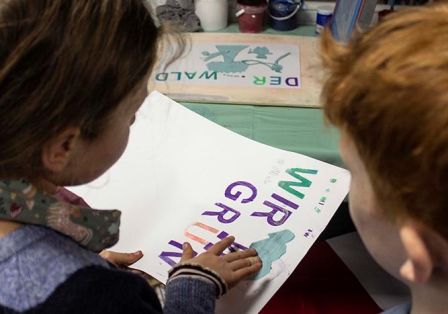 Zwei Kinder vor einem Druck mit der Aufschrift: Wir Gr&uuml;nen